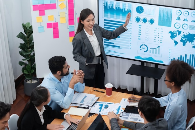 Jonge Aziatische zakenvrouw presenteert een dashboard voor gegevensanalyse op het tv-scherm in een moderne vergadering Bedrijfspresentatie met een groep zakenmensen in de vergaderzaal Concord