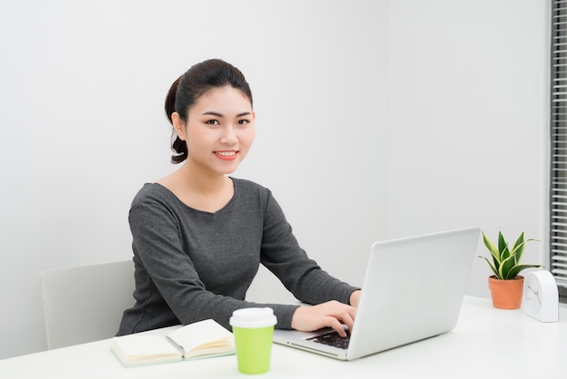 Jonge Aziatische zakenvrouw zittend aan een bureau en werken?