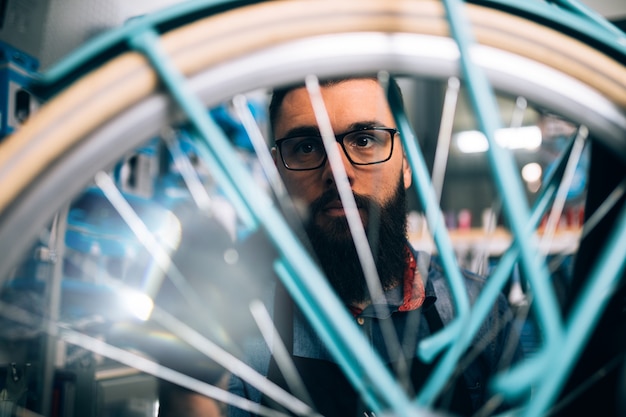 Jonge baard fietsenmaker repareren van fietsen in een werkplaats.