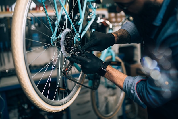 Jonge baard fietsenmaker repareren van fietsen in een werkplaats.