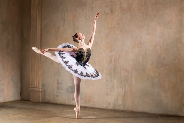 Jonge ballerina in een witte tutu dansen in een spotlight in een vintage scène