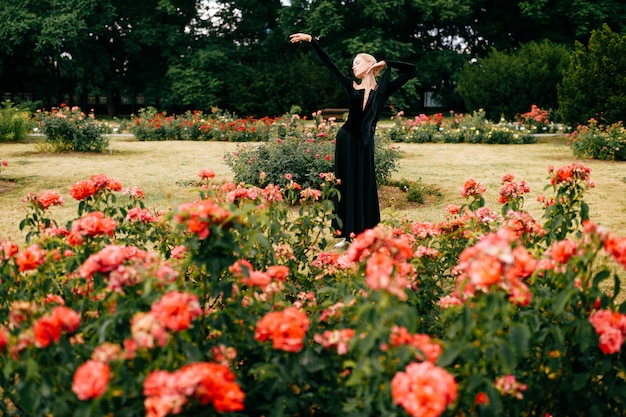 Jonge ballerina in zwarte jurk poseren en ballet poses tonen in zomer park.