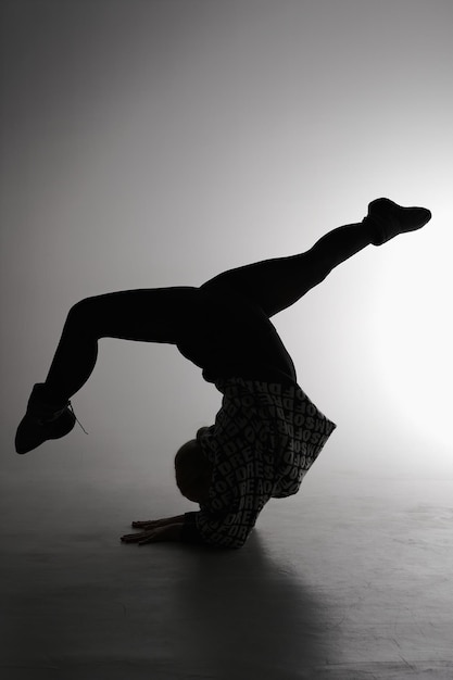 Jonge balletdanser die zich voordeed op een grijze achtergrond Ballerina draagt in zwarte jurk en dansschoenen Het silhouet van de omtrek schieten van girl