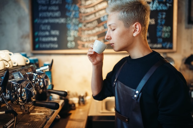 Foto jonge barista proeft vers bereide koffie