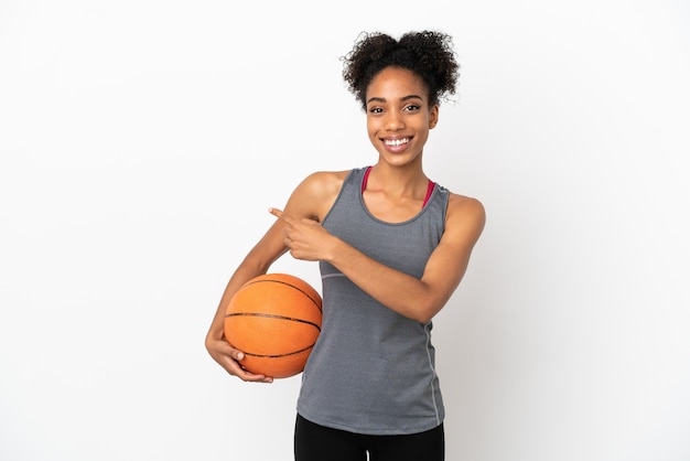 Jonge basketbalspeler latijnse vrouw geïsoleerd op een witte achtergrond basketbal spelen en wijzend naar de laterale