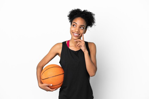 Jonge basketbalspeler latijnse vrouw geïsoleerd op een witte achtergrond die een idee denkt terwijl ze omhoog kijkt