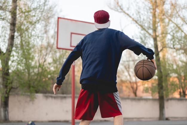 Foto jonge basketbalspeler opleiding om buiten op het asfalthof te druppelen