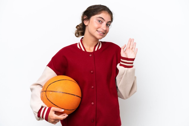 Jonge basketbalspeler vrouw geïsoleerd op een witte achtergrond saluerend met de hand met gelukkige expression