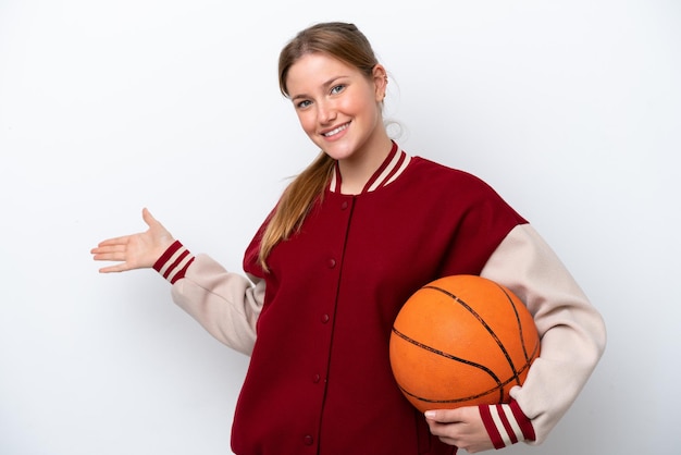 Jonge basketbalspelervrouw geïsoleerd op een witte achtergrond die de handen naar de zijkant uitstrekt om uit te nodigen om te komen