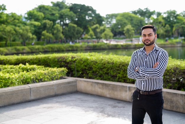 Jonge, bebaarde indiase zakenman ontspannen in het park