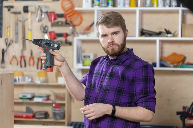 Jonge, bebaarde man aan het werk in de meubelfabriek.