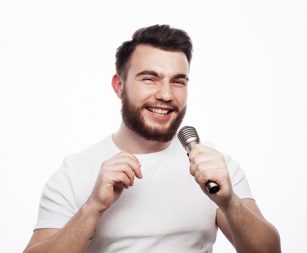 Jonge, bebaarde man in wit overhemd zingt in microfoon