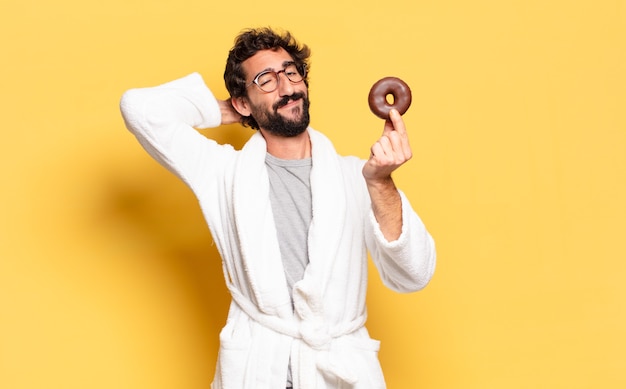 Jonge, bebaarde man met een badjas met een chocolade donut