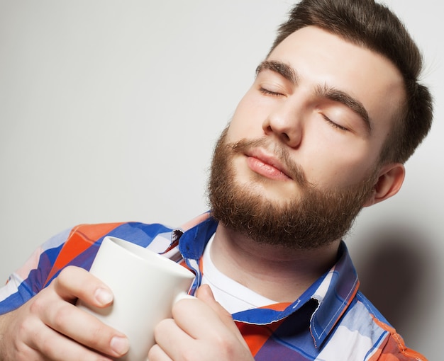 Jonge, bebaarde man met een kopje koffie