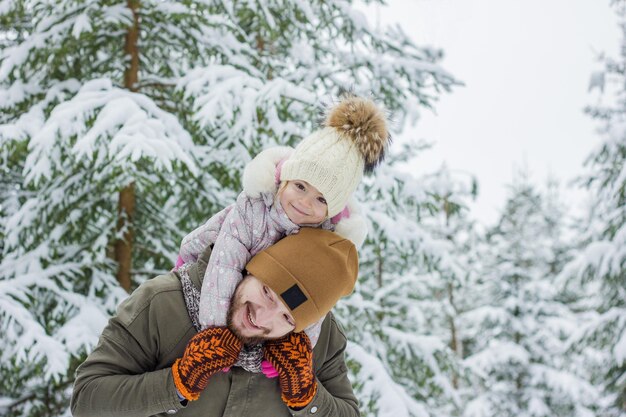 Jonge, bebaarde man met klein meisje veel plezier in het besneeuwde bos in de winter