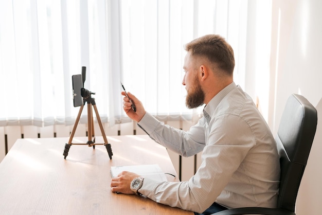 Jonge, bebaarde man met smartphone en tijdschema Kladblok Close-up bedrijf