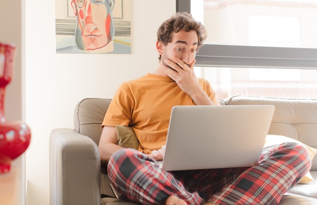 Jonge, bebaarde man op een bank met een laptop