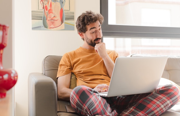 Jonge, bebaarde man op een bank met een laptop