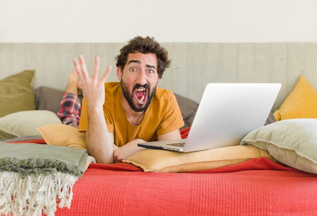 Jonge, bebaarde man op een bed met een laptop