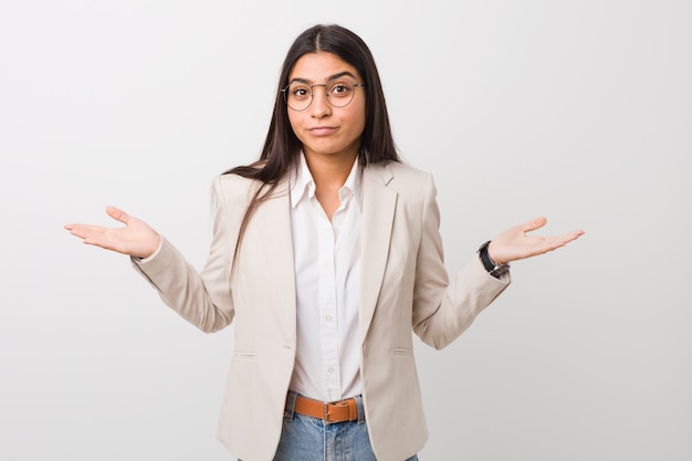 Jonge bedrijfs Arabische vrouw die tegen witte wordt geïsoleerd die en schouders in het vragen van gebaar twijfelen ophalen.