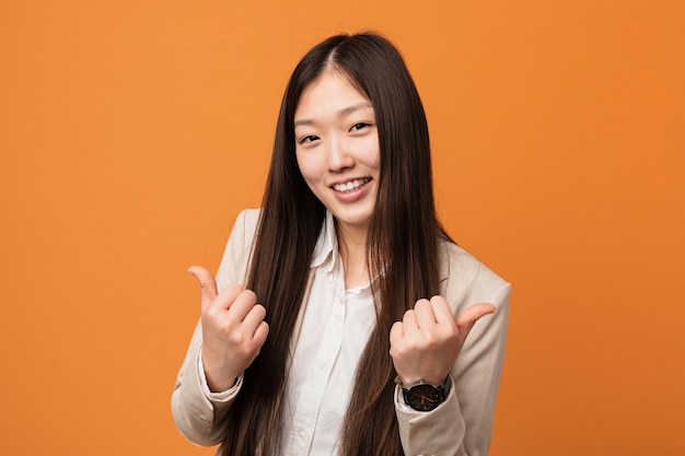 Jonge bedrijfs Chinese vrouw die beide duimen opheft, glimlachend en zeker.