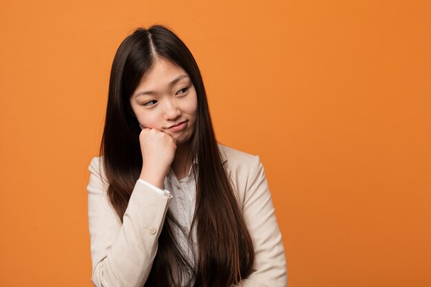 Jonge bedrijfs Chinese vrouw die droevig en nadenkend voelt, bekijkend exemplaarruimte.