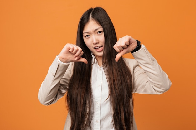 Jonge bedrijfs chinese vrouw die duim toont en afkeer uitdrukt.