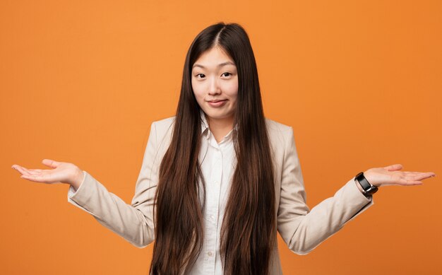 Jonge bedrijfs Chinese vrouw die en hem schouders ophaalt in gebaar vragend ophaalt.