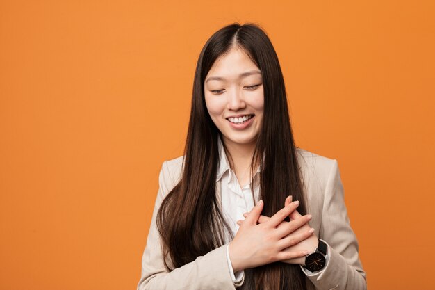 Jonge bedrijfs Chinese vrouw die houdend handen op hart lachen, concept geluk.