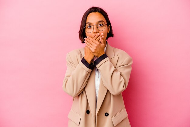 Jonge bedrijfs gemengde rasvrouw die op roze muur wordt geïsoleerd die geschokt die mond behandelt met handen