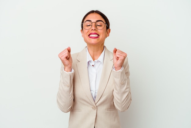 Jonge bedrijfs Kaukasische vrouw die op witte achtergrond wordt geïsoleerd die vuist opheft, zich gelukkig en succesvol voelt. Overwinning concept.