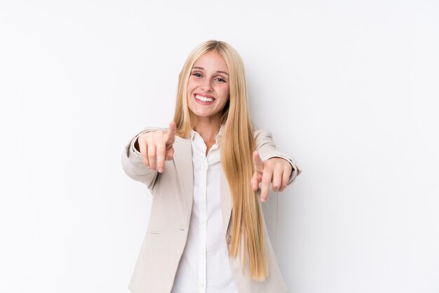 Jonge bedrijfsblonde vrouw op witte muur vrolijke glimlachen die aan voorzijde richten.