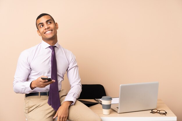 Jonge bedrijfsmens in een en bureau dat omhoog lacht kijkt