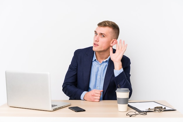 Jonge bedrijfsmens met laptop die een roddel proberen te luisteren.