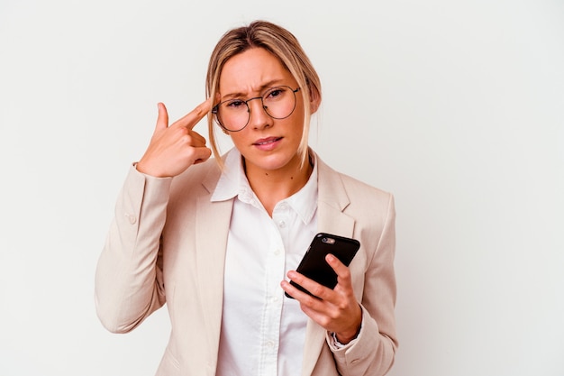 Jonge bedrijfsvrouw die mobiel houdt dat op witte muur wordt geïsoleerd die een teleurstellinggebaar met wijsvinger toont