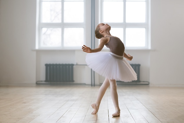 Jonge begaafde danseres in tutu-jurk die balletdans studeert op dansschool