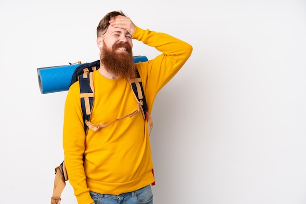 Jonge bergbeklimmermens met een grote rugzak over het geïsoleerde witte muur lachen