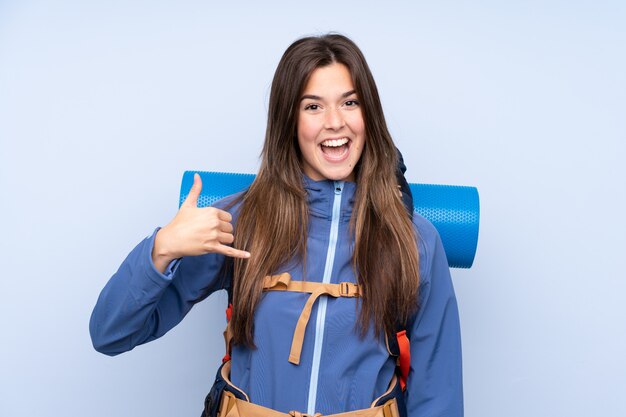 Jonge bergbeklimmervrouw met een grote rugzak over geïsoleerde muur