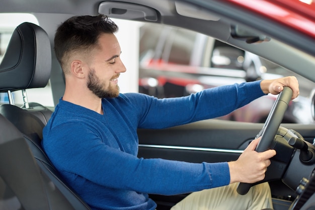 Jonge bezoeker van autosalonzitting bij voorstoel in auto.