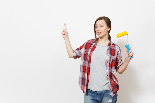 Jonge bezorgde vrouw met verfroller voor muurschildering en wijsvinger omhoog op kopieerruimte geïsoleerd op een witte achtergrond. Instrumenten voor renovatie appartement kamer. Reparatie huis concept.