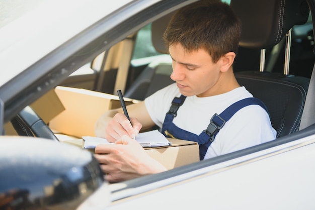 Foto jonge bezorger die lijst op klembord in de auto controleert