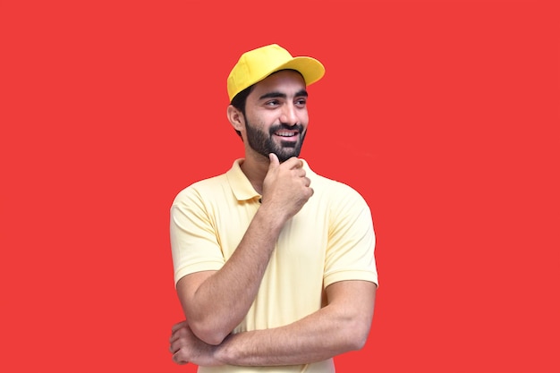 jonge bezorger in geel t-shirt glimlachend over rode achtergrond Indiase Pakistaanse model