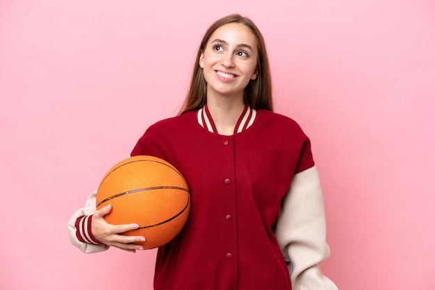 Jonge blanke basketbalspeler vrouw over geïsoleerd op roze achtergrond die een idee denkt terwijl ze omhoog kijkt