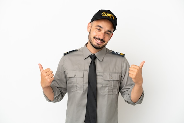 Jonge blanke beveiligingsman geïsoleerd op een witte achtergrond met een duim omhoog gebaar en glimlachen