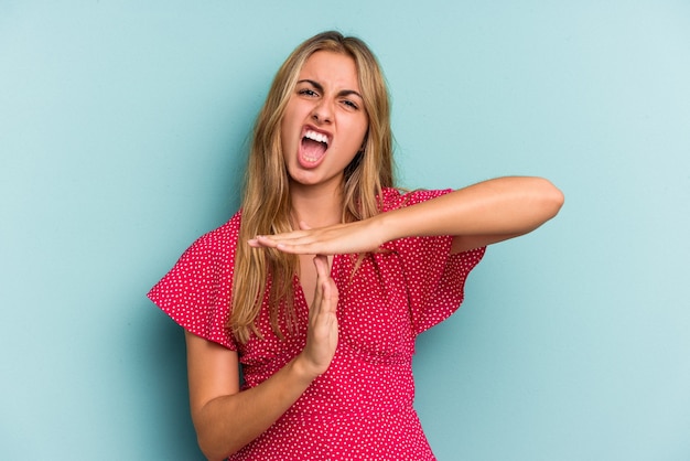 Jonge blanke blonde vrouw geïsoleerd op blauwe achtergrond met een time-out gebaar.