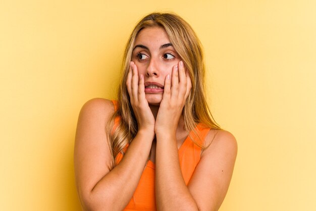 Jonge blanke blonde vrouw geïsoleerd op gele achtergrond bang en bang.