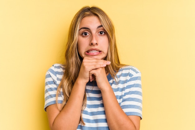 Jonge blanke blonde vrouw geïsoleerd op gele achtergrond bidden voor geluk, verbaasd en mond openen op zoek naar voren.