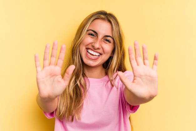 Jonge blanke blonde vrouw geïsoleerd op gele achtergrond met nummer tien met handen.