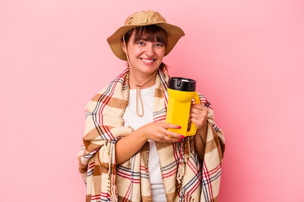 Jonge blanke bochtige vrouw met lantaarn geïsoleerd op roze achtergrond lachen en plezier maken.