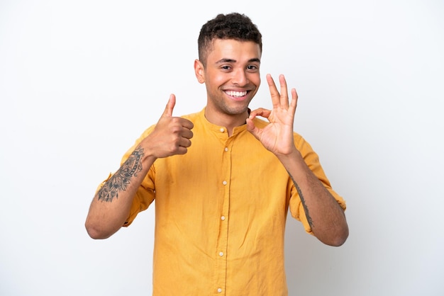 Jonge blanke Braziliaanse man geïsoleerd op een witte achtergrond met ok teken en duim omhoog gebaar